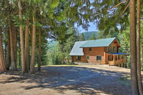 a log cabin in the woods with a driveway at Large Cabin with Fire Pit and Grill on 34 Acres! in Sagle