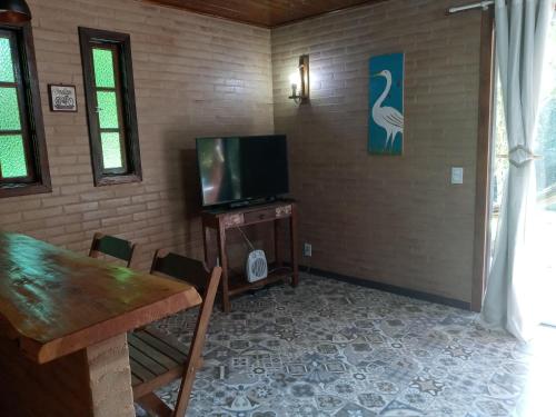 a dining room with a table and a television at Eco Chalés Águas Claras in Lumiar