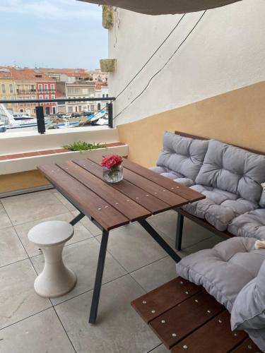 einen Holztisch und ein Sofa auf dem Balkon in der Unterkunft Le Petit Bijou Sète, quatre appartements au centre ville, trois avec vue canal in Sète