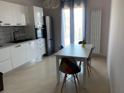 una cocina con armarios blancos y una mesa con sillas. en Casa Etna Nicolosi, en Nicolosi
