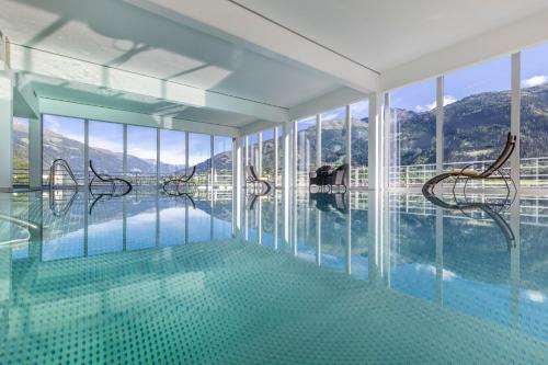 uma piscina com cadeiras num quarto com janelas em Vergeiner's Hotel Traube em Lienz