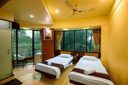 a bedroom with two beds and a ceiling fan at La Hotel Metro near BKC in Mumbai
