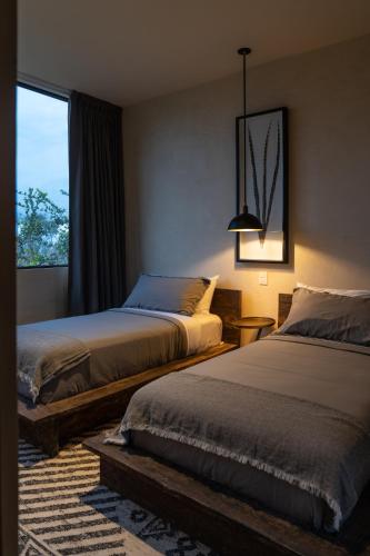 a bedroom with two beds and a window at Unho Tulum in Tulum