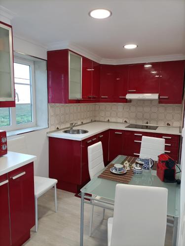 a kitchen with red cabinets and a table and chairs at O Chaleco in San Ciprián