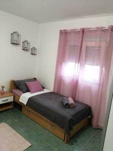a bedroom with two beds and pink curtains at Holiday house Lara in Starigrad-Paklenica