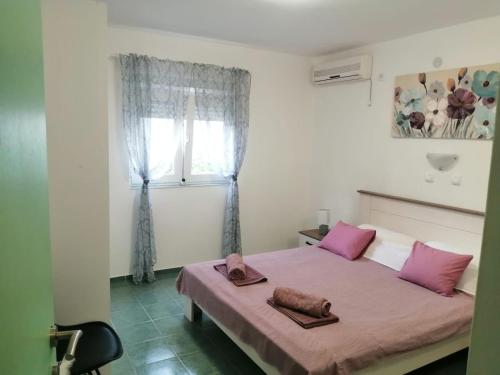 a bedroom with a bed with pink pillows and a window at Holiday house Lara in Starigrad-Paklenica