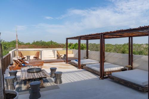 a roof deck with a gazebo and chairs at Unho Tulum in Tulum