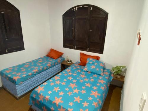 a bedroom with two beds with orange pillows at Casa de Praia - Alcobaça-BA - em frente ao Condomínio Gaivotas in Alcobaça
