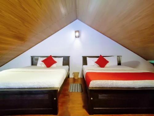 two beds with red pillows in a attic bedroom at Moon Plains Luxury Apartments in Nuwara Eliya