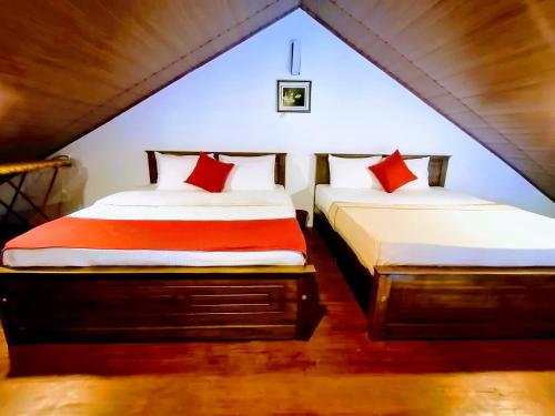 two beds in a attic room with red pillows at Moon Plains Luxury Apartments in Nuwara Eliya