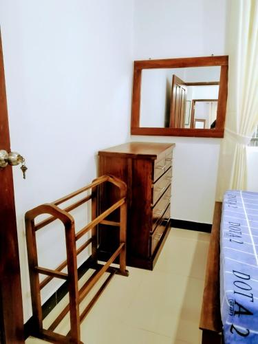 a bedroom with a wooden dresser and a mirror at Moon Plains Luxury Apartments in Nuwara Eliya