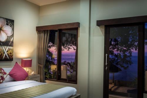 a bedroom with a bed and a large window at The Beach Front Villas - North Bali in Kubutambahan