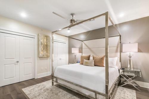 um quarto com uma cama de dossel com lençóis e almofadas brancos em The Creole Queen em Nova Orleans