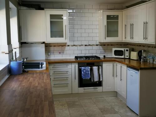 a kitchen with white cabinets and a stove top oven at BRIGSTOCK HOLIDAYS HOUSE in Manchester