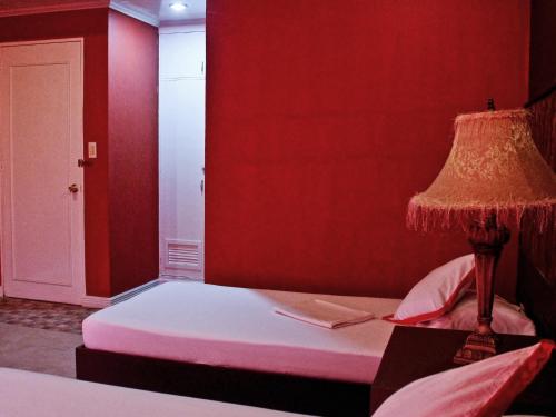 a red room with a bed with a lamp on it at RB Bed and Breakfast in Kalibo