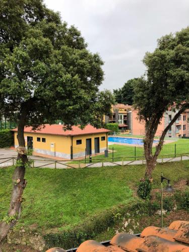 2 arbres dans un parc avec un bâtiment et une piscine dans l'établissement MARINA LLANES IV, à Llanes