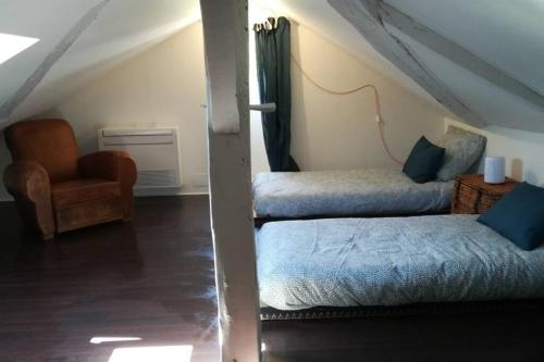 Cette chambre mansardée comprend deux lits et une chaise. dans l'établissement La maison d'Amatxi, à 150m de la plage, à Bidart