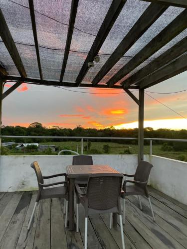 a table and chairs on a deck with a sunset at ZUGI INN HOTEL in Leticia