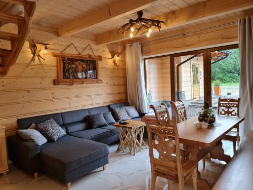 a living room with a couch and a table at Żabie Dworki Witów Luxury Chalets & SPA in Witów