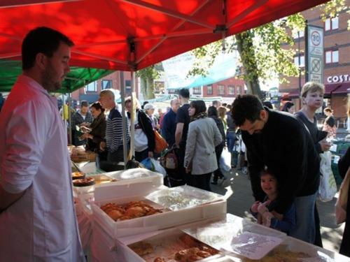 a crowd of people standing around a market with food at Charlotte Guest House in London