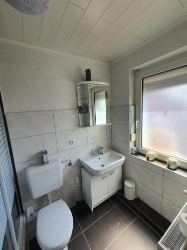 La salle de bains est pourvue de toilettes, d'un lavabo et d'une fenêtre. dans l'établissement FEWO BEI LEHMANNS, à Werl