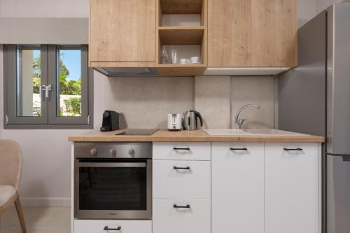 a kitchen with white cabinets and a sink and a stove at Onore Luxury Suites in Kato Korakiana