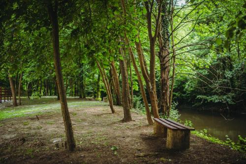 a bench in a park with trees and a river at Restoran sa prenoćištem Gornjak in Krepoljin