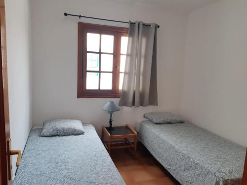 2 łóżka pojedyncze w pokoju z oknem w obiekcie La Laja 13 w mieście Playa Blanca