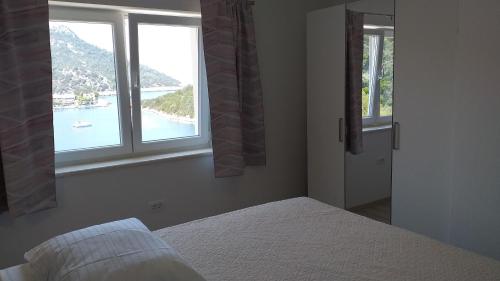 1 Schlafzimmer mit 2 Fenstern und Blick auf das Wasser in der Unterkunft APARTMAN KARLA in Lastovo