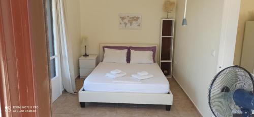 a bedroom with a white bed and a fan at Efi Loutses in Anapaftíria