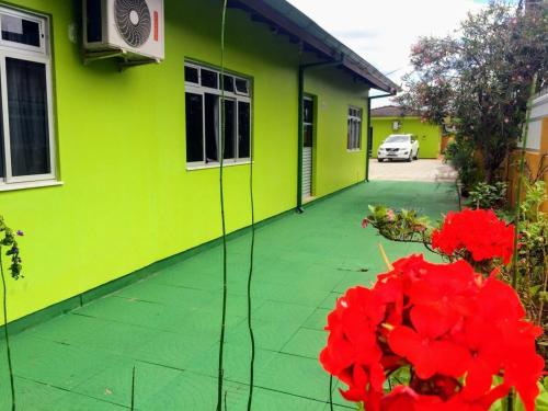 a green house with red flowers in front of it at Pousada Morada do Sol in Florianópolis