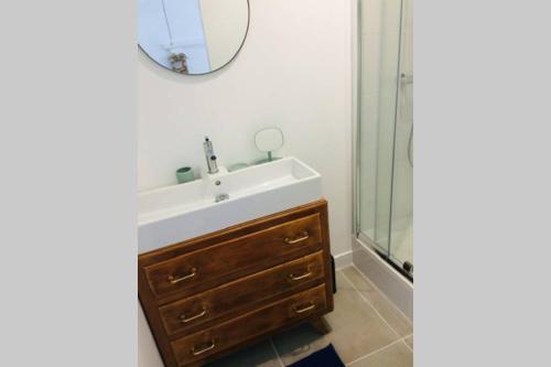 a bathroom with a sink and a mirror and a shower at L'annexe des Cigales, à l'ombre des chênes lièges in Capbreton