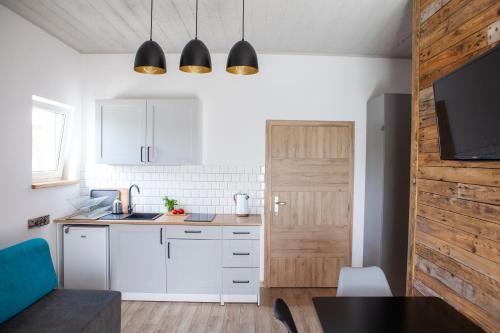 a kitchen with white cabinets and a wooden door at 4 Pokoje Swory in Swornegacie 