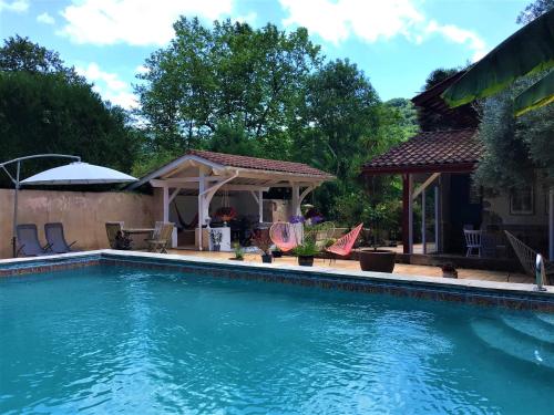 a swimming pool with chairs and a gazebo at Kapera Maison d'Hotes in Macaye