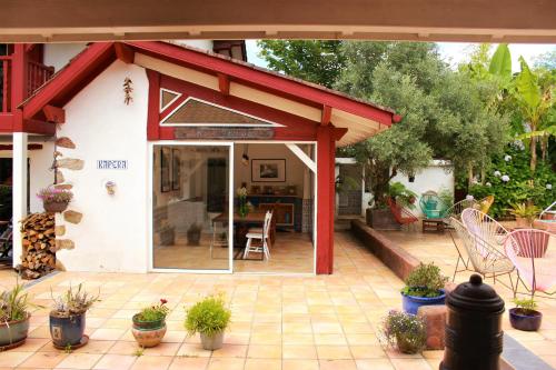 a patio with a red awning and some plants at Kapera Maison d'Hotes in Macaye