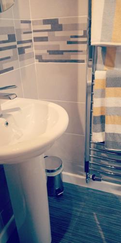 bagno con lavandino bianco e doccia di Cosy place a Derby