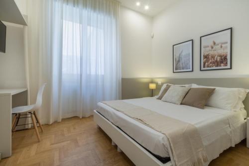 a white bedroom with a bed and a desk at Guesthouse Libeticus in Cagliari
