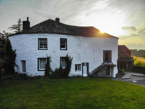 a white house with the sun setting behind it at Fiddleback Farm in Wigton