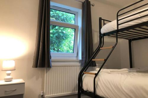 a bedroom with two bunk beds and a window at Clives Place - End of terrace two bedroom cottage in Cwm-brân