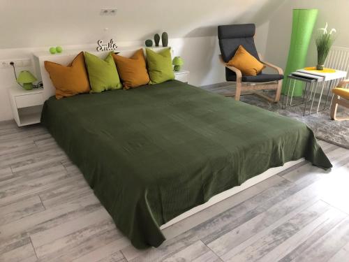 a large green bed in a room with a chair at Dominik Apartmanház in Velence