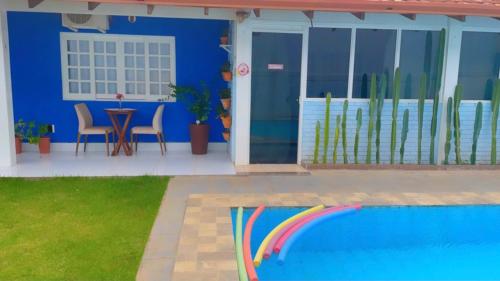a blue house with a pool and a table and chairs at happiness house/ casa da felicidade in Cuiabá