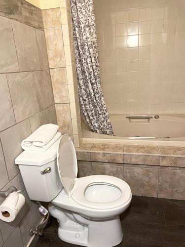 a bathroom with a white toilet and a bath tub at Scottish Inn Near the Falls and Casino in Niagara Falls
