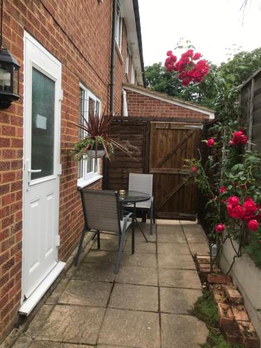 a patio with a table and a door and flowers at Studio-2 Staines,Heathrow, London-own entrance in Staines