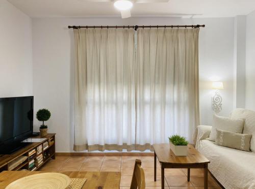 - un salon avec un canapé, une télévision et une table dans l'établissement Apartamento Conil Santa Clara, à Conil de la Frontera