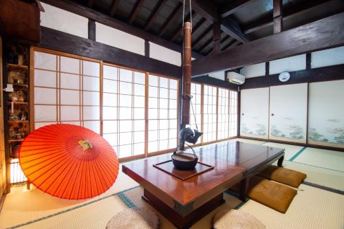 an orange umbrella and a table in a room with windows at Kominka Wagaya in Higashi-osaka