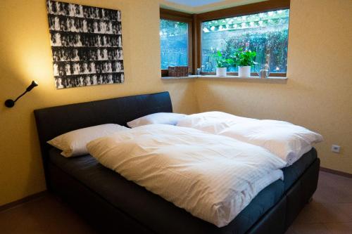 uma cama com lençóis brancos e uma janela num quarto em Ferienwohnung grüne Oase em Maulbronn