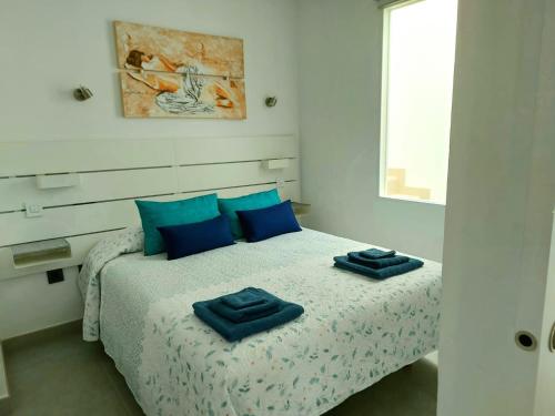 um quarto com uma cama com almofadas azuis em Casa SOLEADA SUNNY House em Playa del Burrero