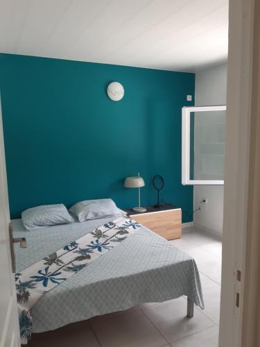 - une chambre avec un mur bleu et un lit dans l'établissement La Poulette amazonienne, à La Mauny