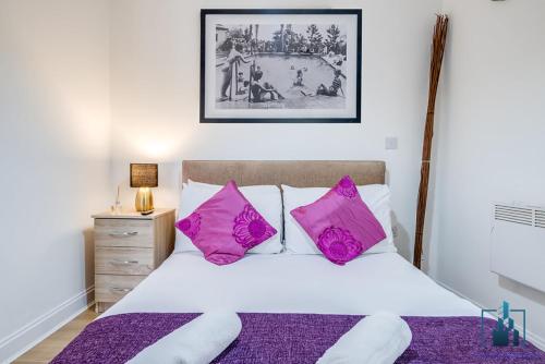 a bedroom with a bed with pink pillows at City View Apartments Birmingham City Centre in Birmingham