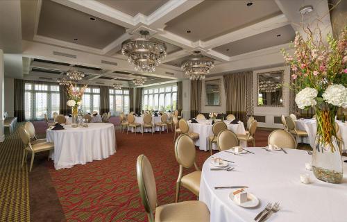 una sala de banquetes con mesas y sillas blancas y lámparas de araña en The Birchwood en San Petersburgo